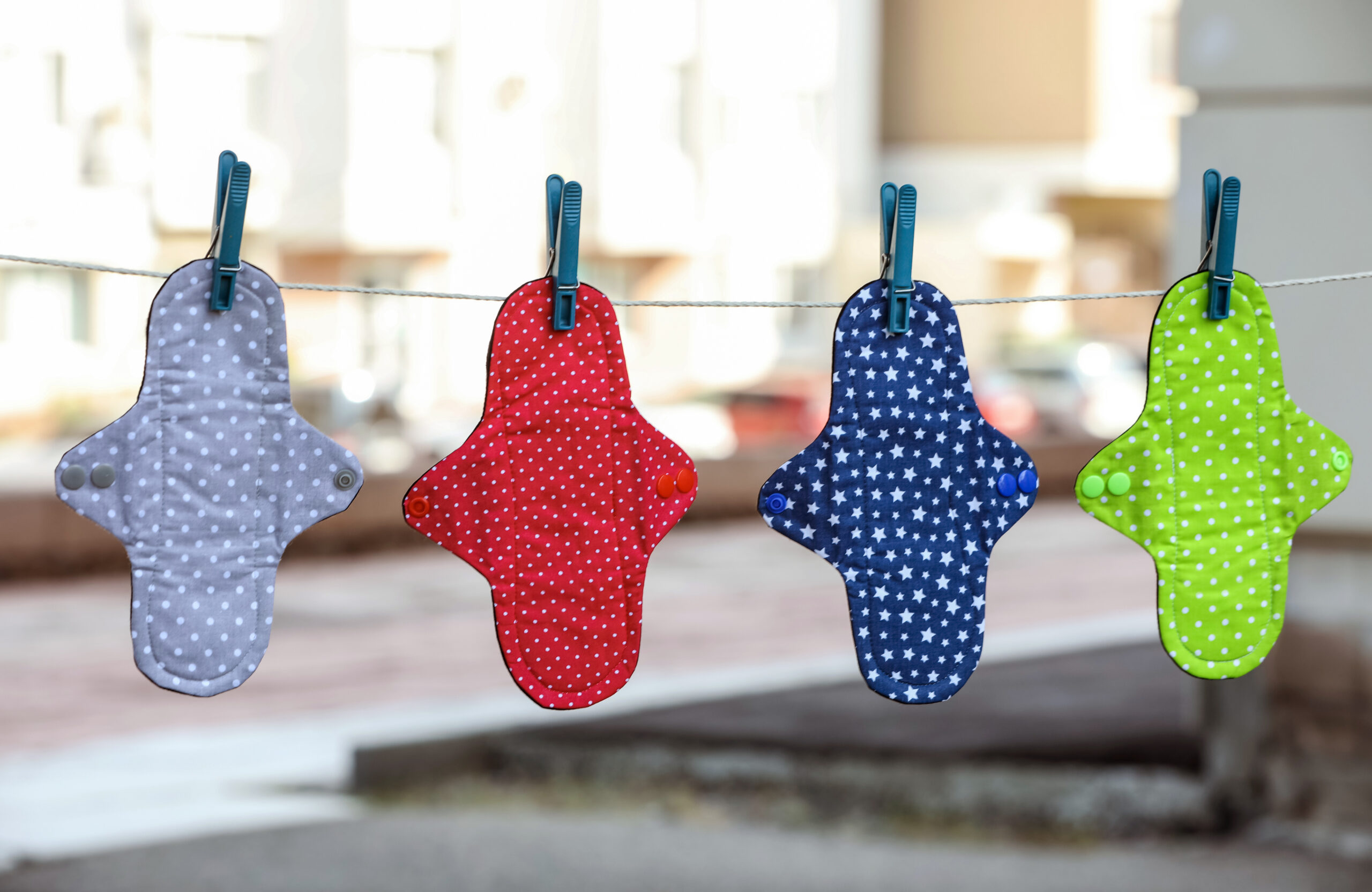 Viele verschiedene Menstruationsbinden aus Stoff, die draußen an einer Leine hängen.
